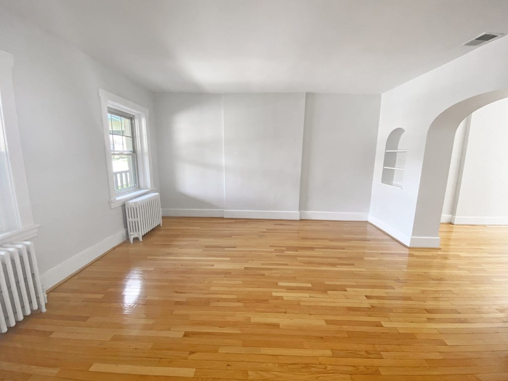 A room with wooden flooring and white walls.