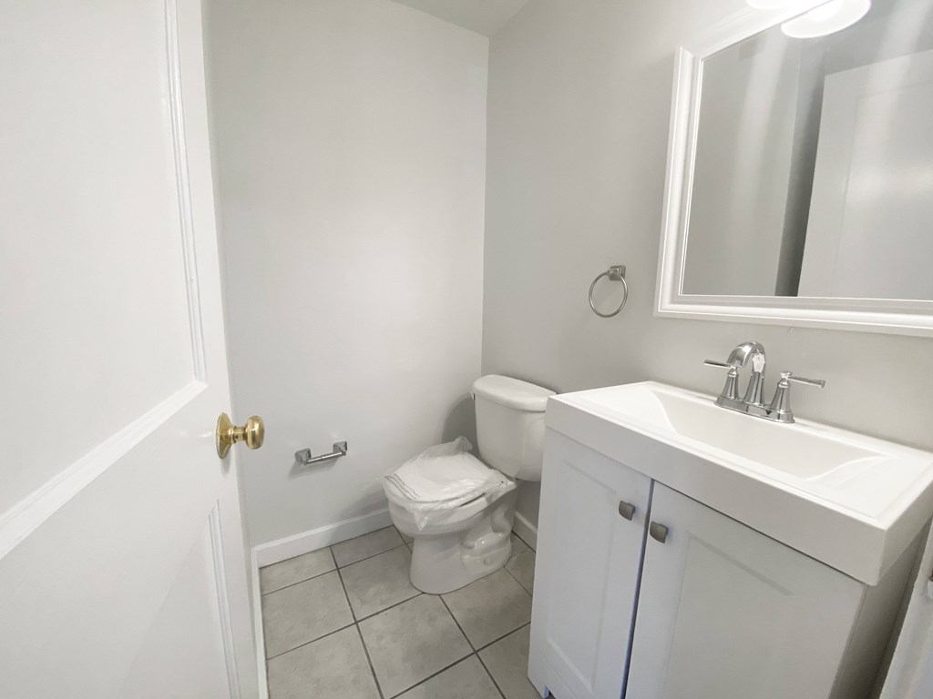 A white bathroom with a toilet, sink, and mirror.