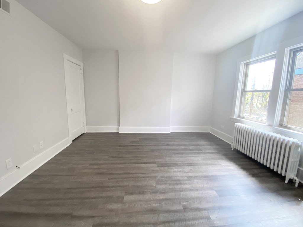 A room with a grey carpet and a white radiator.