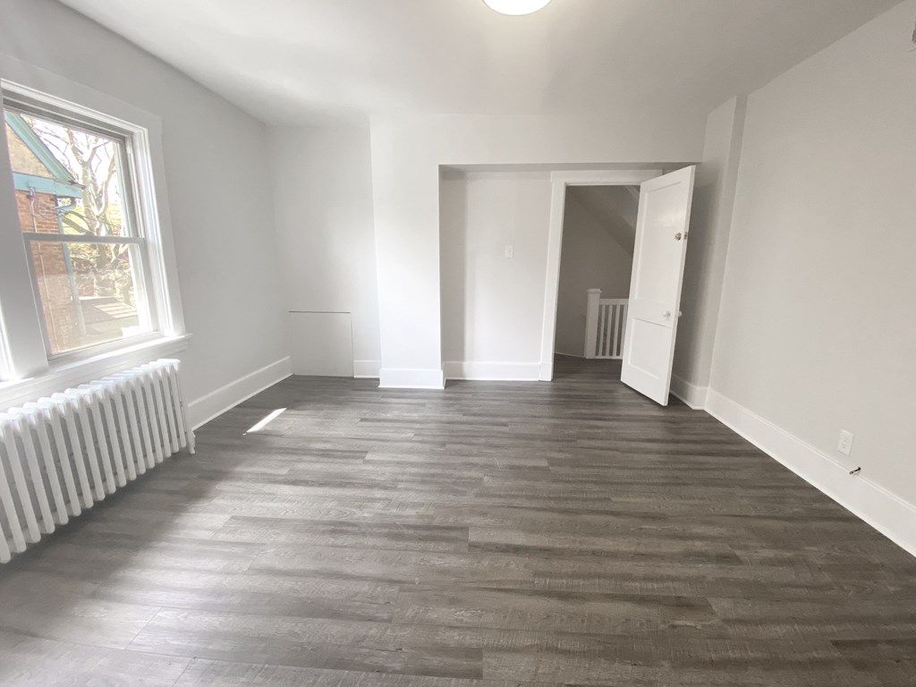 A room with wooden flooring and white walls.