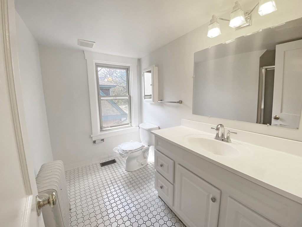 A white bathroom with a toilet, sink, and mirror.