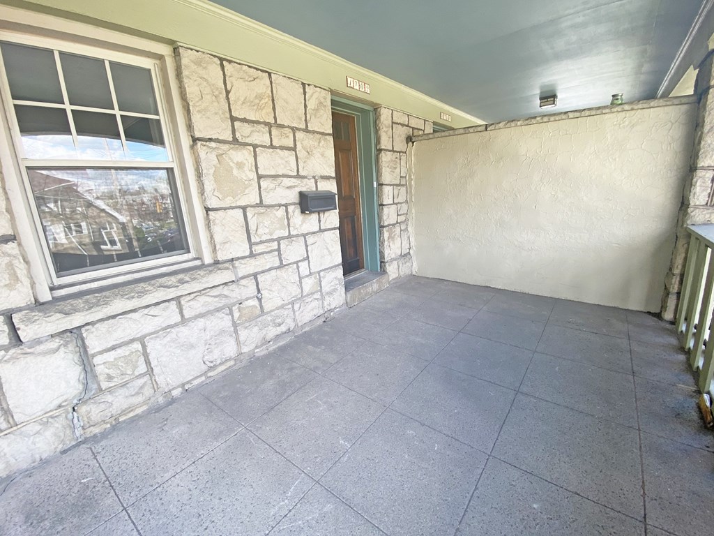 A room with a stone wall and a window showing a house outside.