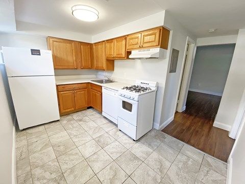 A kitchen with a white refrigerator, white stove, and wooden cabinets.