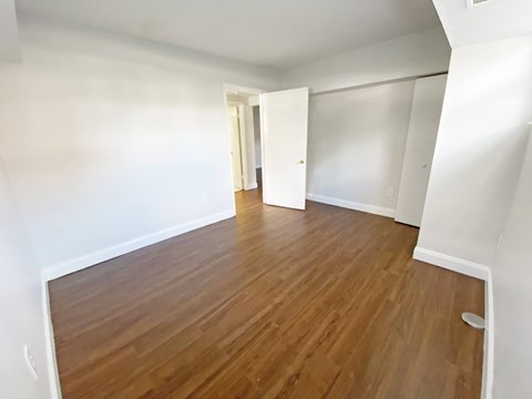 A room with wooden flooring and white walls.