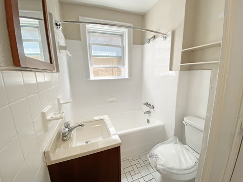 A white toilet is in a small bathroom with a sink and a window.