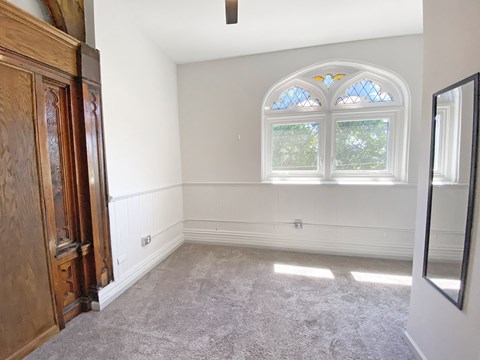 Carpeted Living Space with Unique Window at University Commons Apartments, Oakland, PA