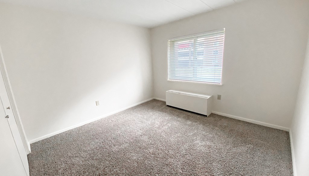 an empty room with a radiator and a window