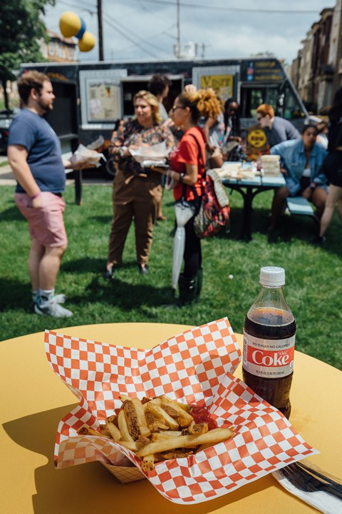 a table with a basket of food and a bottle of coke on it at University Commons Apartments, Oakland, Pittsburgh