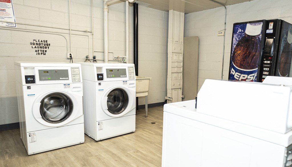 a laundry room with four washing machines and a vending machine