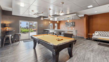 A pool table is in the middle of a room with a couch and a chair.