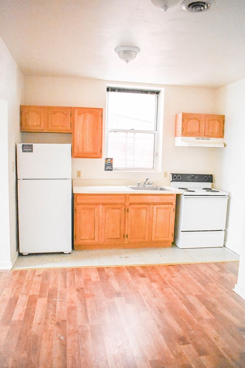 A kitchen with orange cabinets and a white fridge.