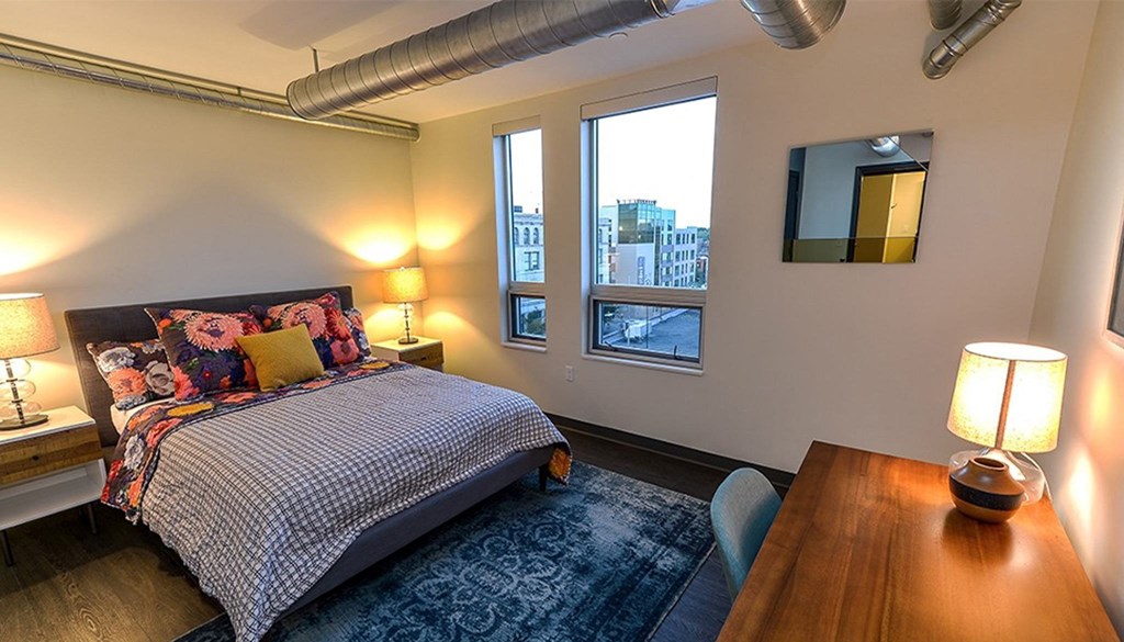 a bedroom with a bed and a desk with two lamps at Walnut on Highland, Pittsburgh, PA