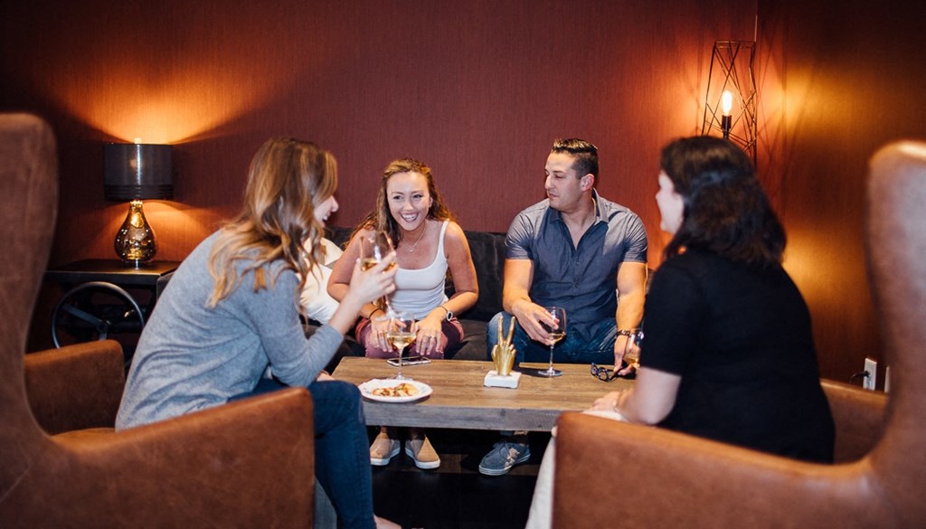 a group of people sitting around a table drinking wine