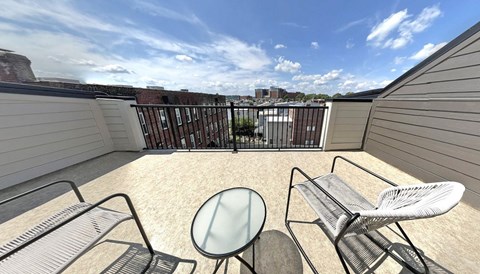 a balcony with two chairs and a glass table