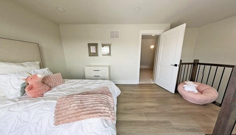 a bedroom with a bed and a pink stuffed toy