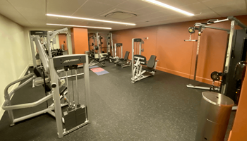 a gym with weights and other equipment in a room with orange walls at The Washington at Chatham, Pittsburgh, PA 15219