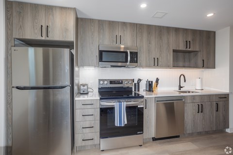 A modern kitchen with a stainless steel refrigerator and oven.