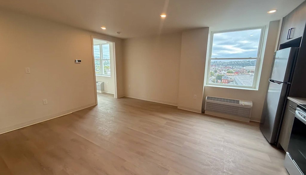 A kitchen with a refrigerator, oven, and a window overlooking a cityscape.at The Jones Tower at the Collective, Pennsylvania, 15203