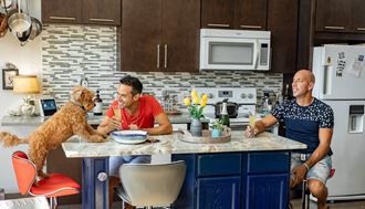 a man and a woman sitting at a kitchen counter with a dog - Photo Gallery 4