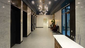 a long hallway with black doors and marble counters and a chandelier  at The Commonwealth Building, Pittsburgh, 15222
