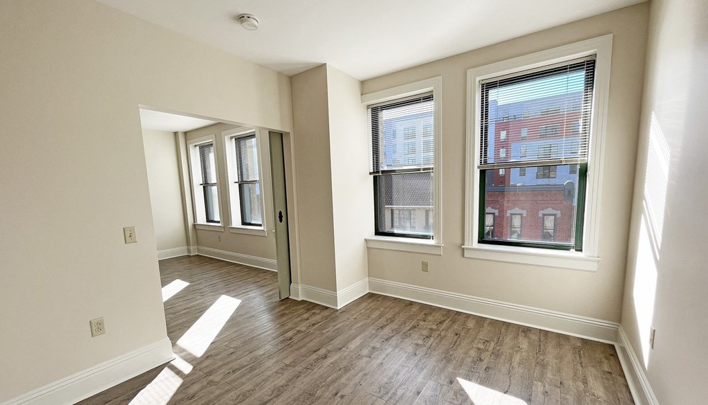 a bedroom with hardwood flooring and three windows at Walnut on Highland, Pittsburgh, PA