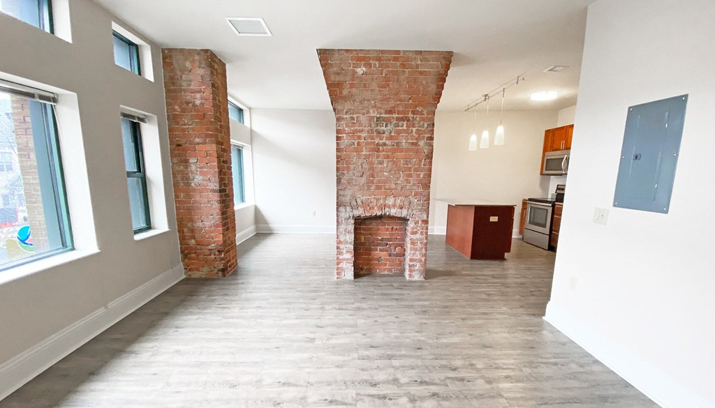 a living room with a fireplace and a kitchen in the background at Walnut on Highland, Pittsburgh, PA