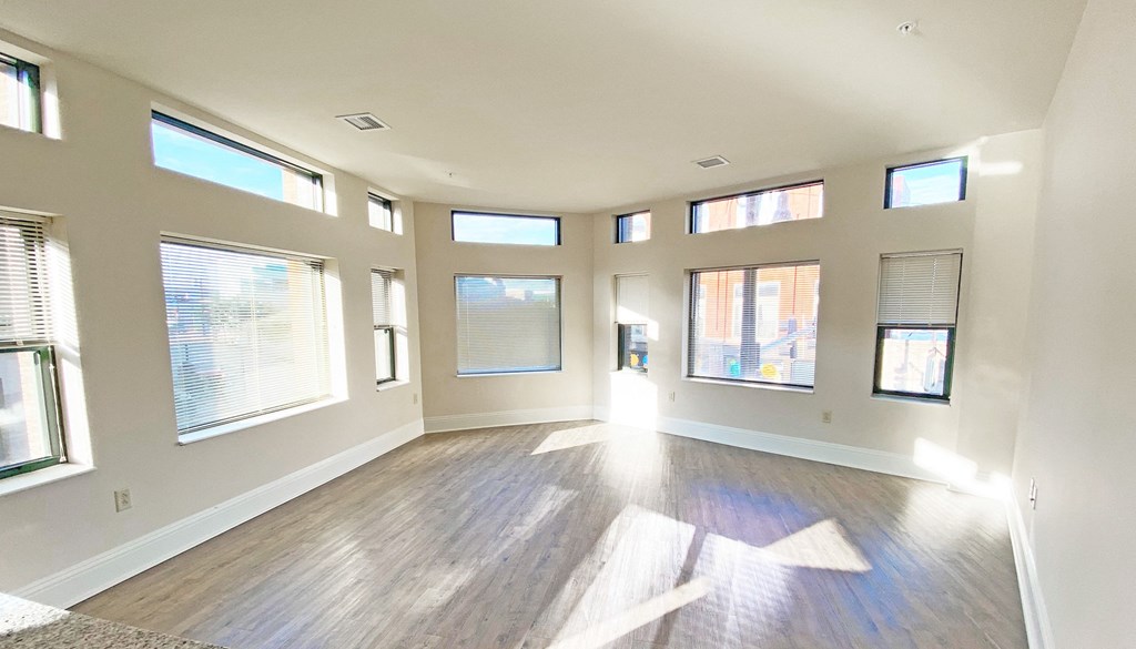 an empty living room with windows and hardwood floors at Walnut on Highland, Pittsburgh, PA