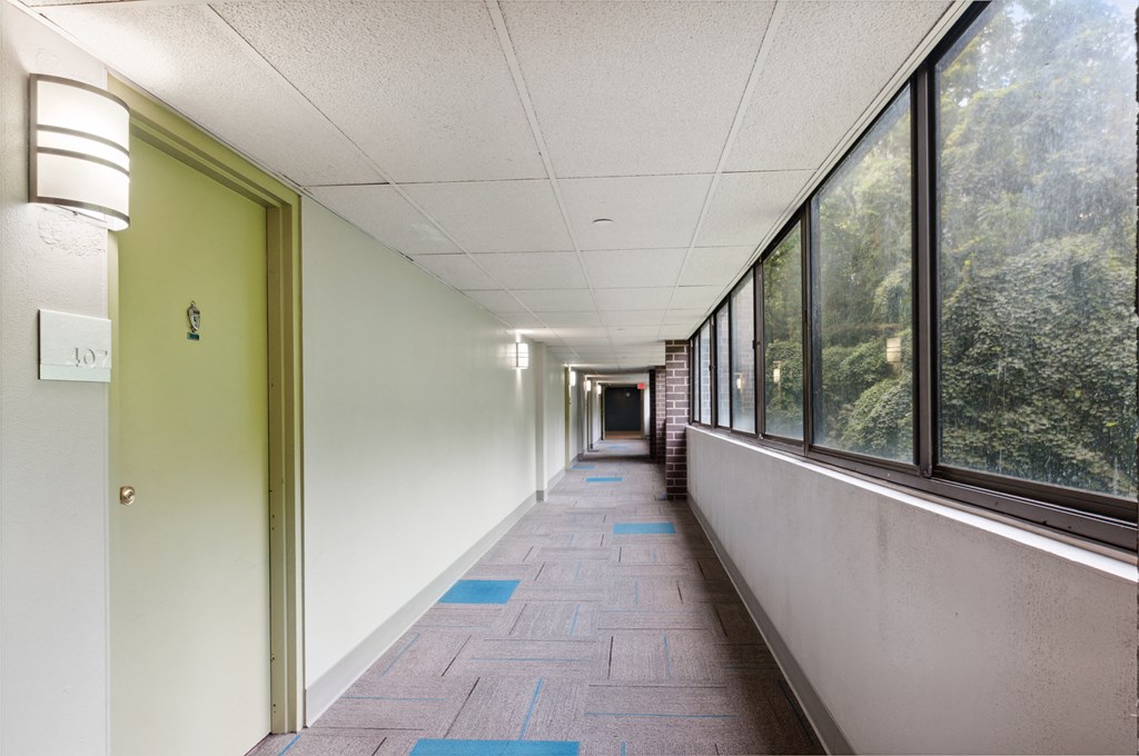 a hallway with large windows and a green door