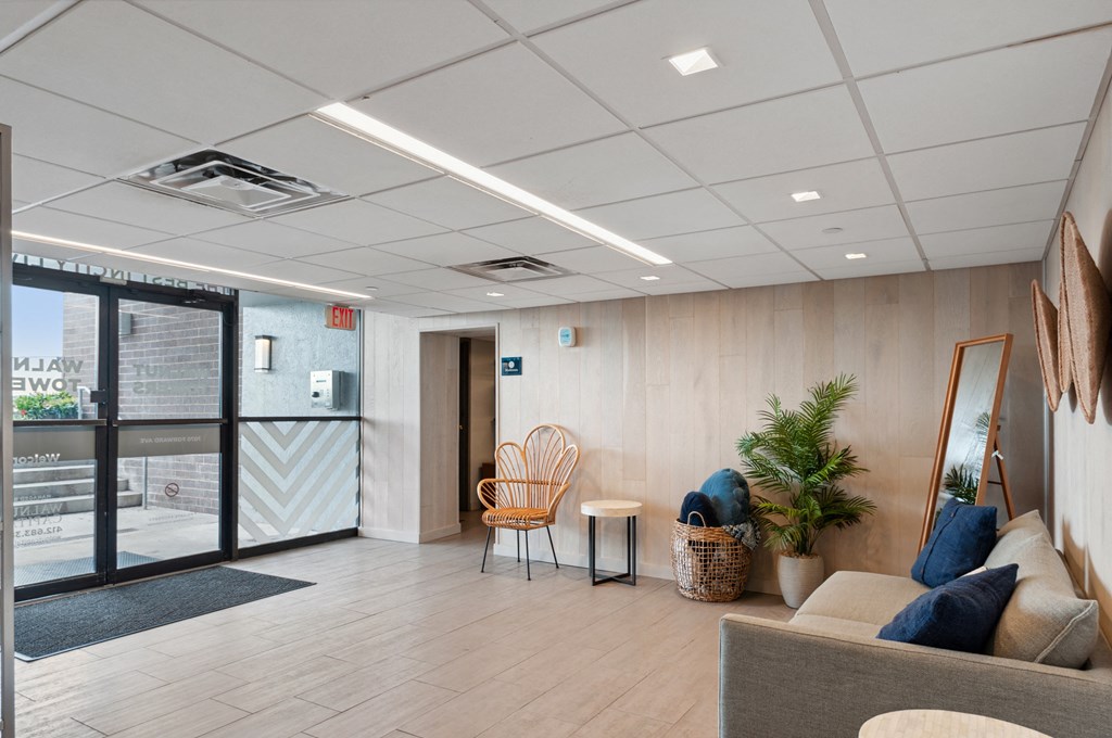a seating area with a sofa chair and a plant in front of a glass door