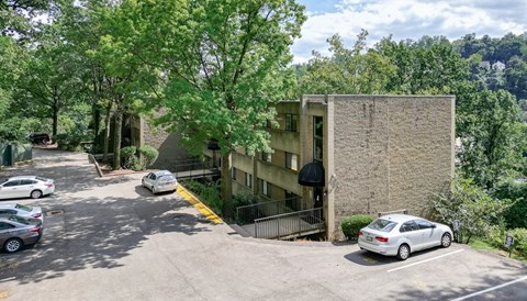 a parking lot with a building in the background and trees in the foreground