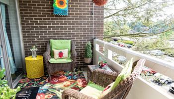 a balcony with wicker chairs and a yellow table