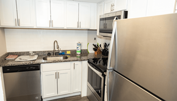 A kitchen with white cabinets and a stainless steel refrigerator.  at Walnut Crossings, Monroeville, PA, 15146