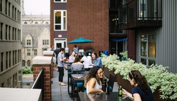people sitting at tables on a patio in front of a brick building