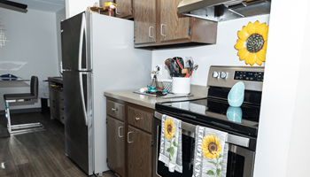 A kitchen with a white fridge and a stove with a sunflower towel on it.  at Walnut Crossings, Monroeville, PA, 15146