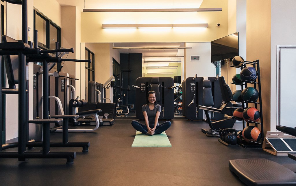 a woman sitting on a yoga mat in a gym at Walnut on Highland, Pittsburgh, PA