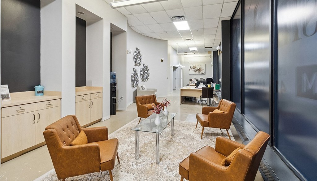 A glass table with a vase of flowers on it is surrounded by four chairs in a modern office. at The Washington at Chatham, Pennsylvania, 15219