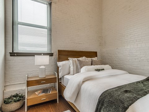A bedroom with a bed, nightstand, and window.