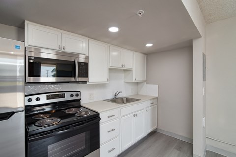 A kitchen with white cabinets and a black stove top oven.