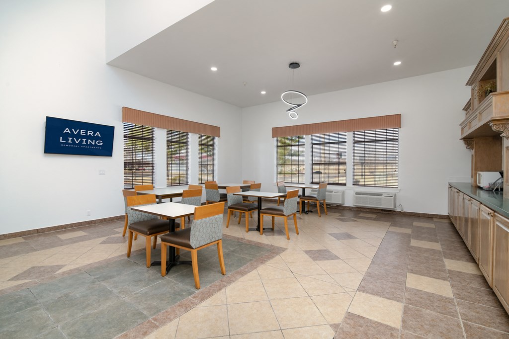 a communal dining room with tables and chairs and a kitchen