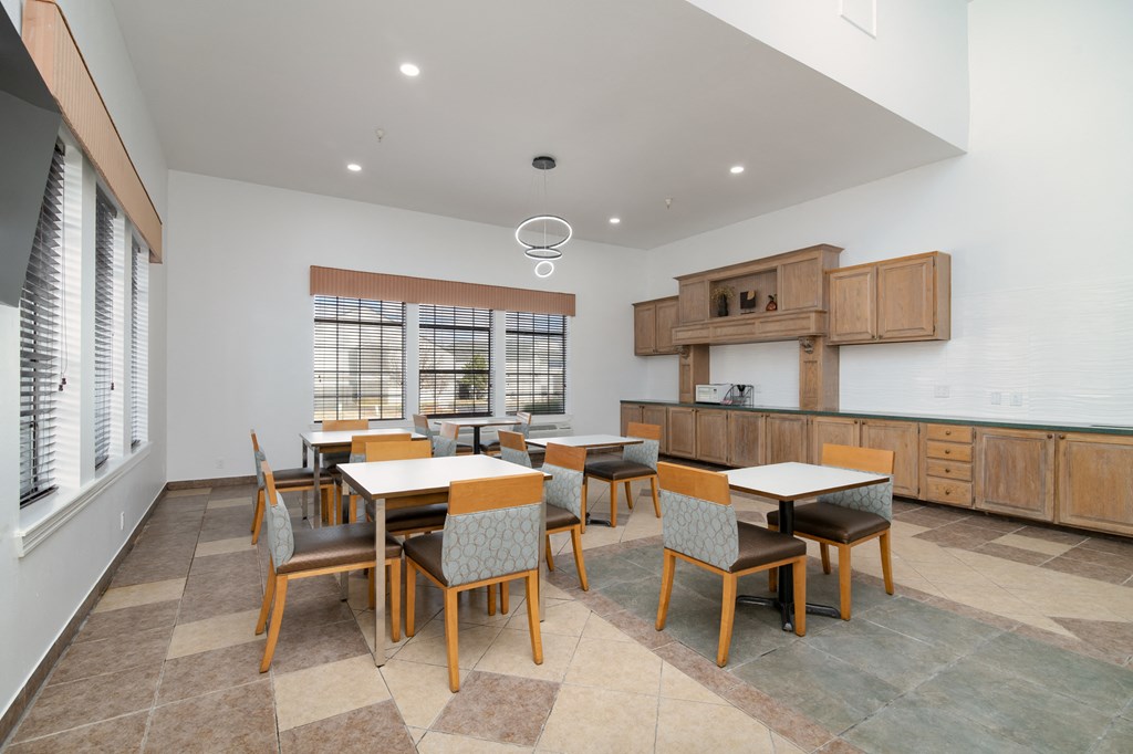 a dining room with tables and chairs and a kitchen