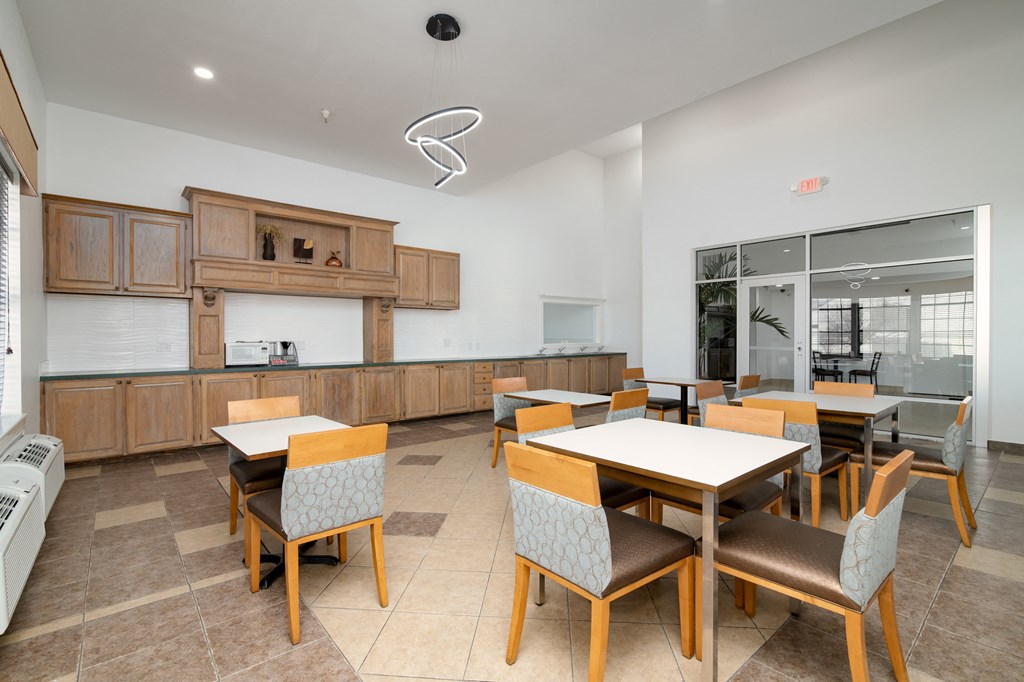 a dining room with tables and chairs and a kitchen