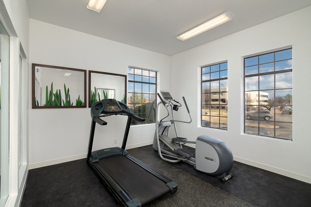 an exercise room with a treadmill and windows