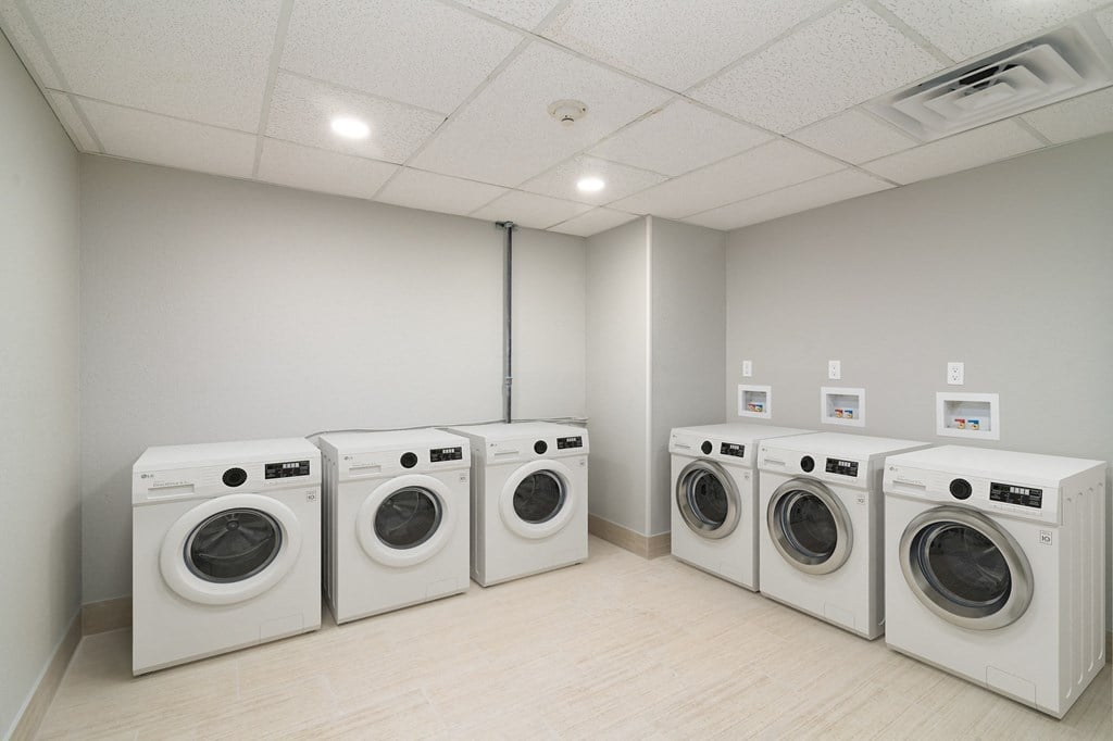 a row of washers and dryers in a laundry room with four washing machines