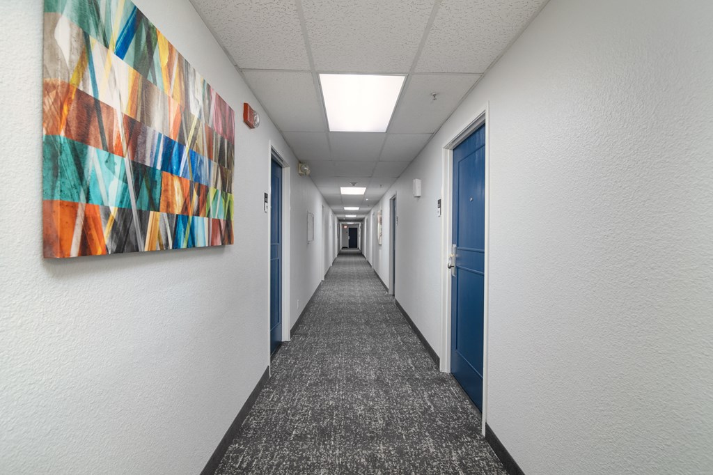 a hallway with blue doors and a colorful painting on the wall