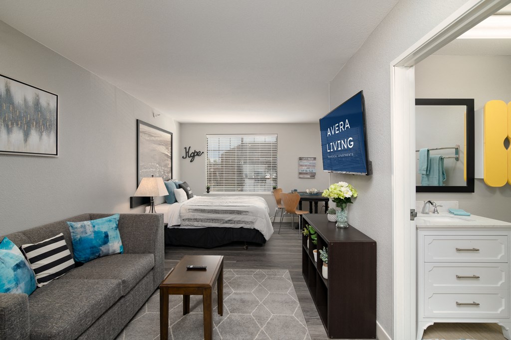 a living room with a couch and a table and a bedroom with a bed