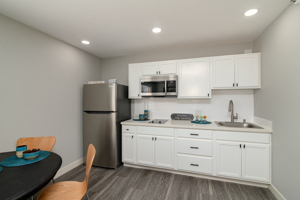 a kitchen with white cabinets and a stainless steel refrigerator