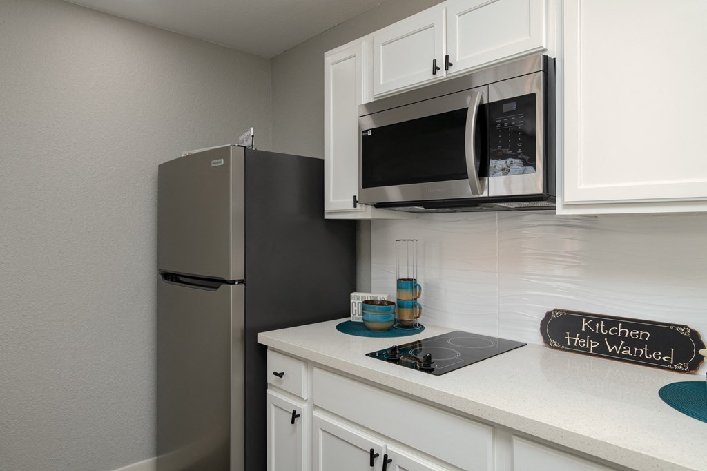 a kitchen with white cabinets and a refrigerator and a microwave