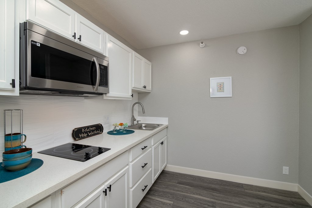 a kitchen with white cabinets and a sink and a microwave