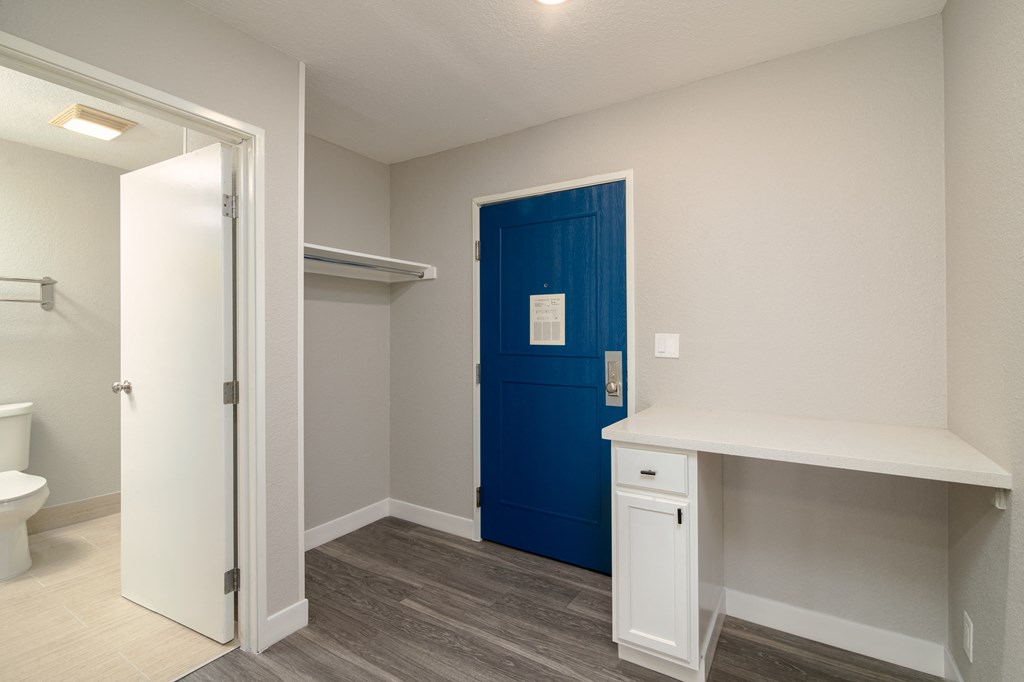 an empty room with a blue door and a white desk