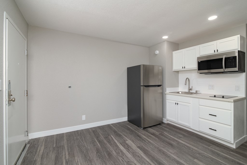 a kitchen with white cabinets and a stainless steel refrigerator